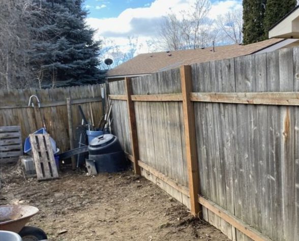 The side-yard fence rebuilt with new posts and rails