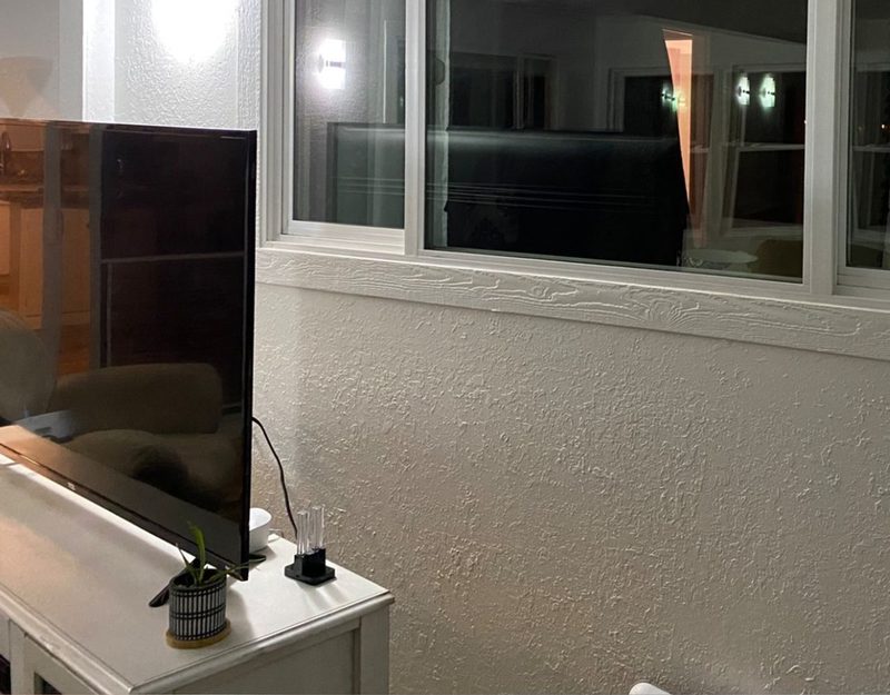 Living-room wall with a TV and damage below the window